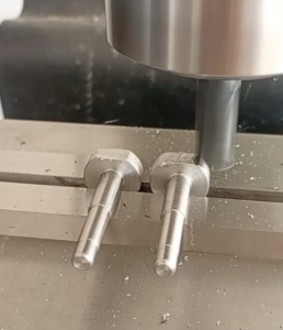 Dos piezas metálicas cilíndricas roscadas siendo maquinadas simultáneamente en un centro CNC